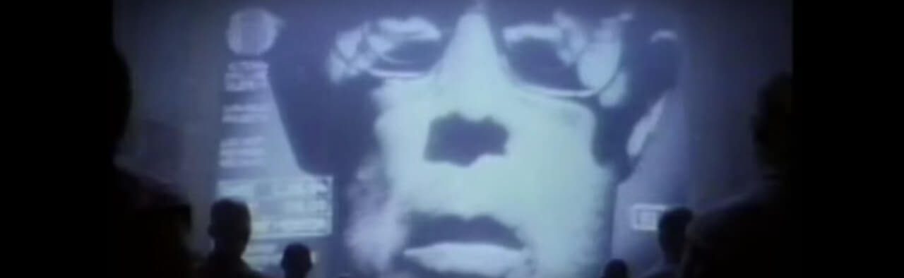 Ghostly face projected on a screen above a crowd