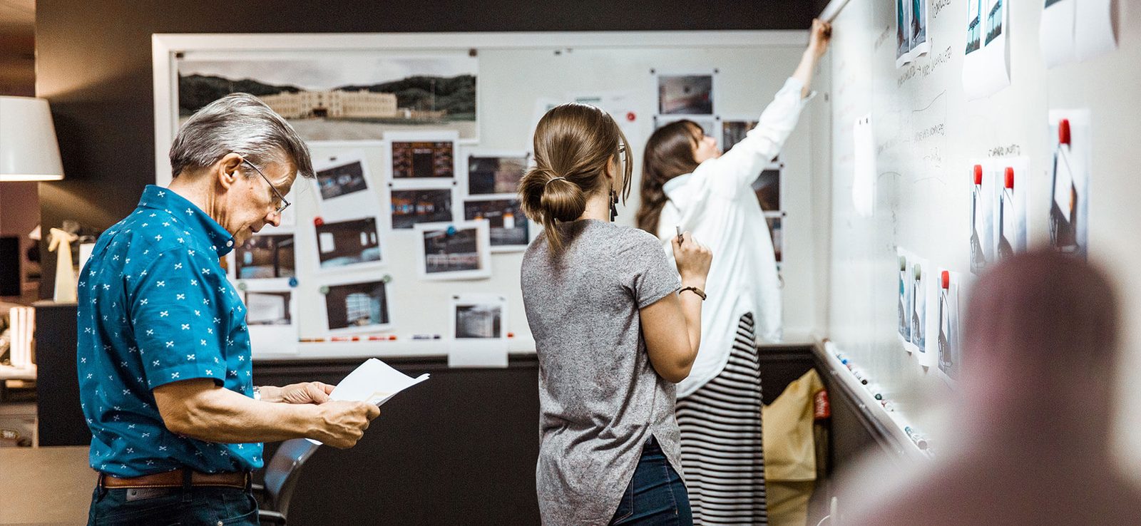 Team reviewing photos and layouts pinned to a wall