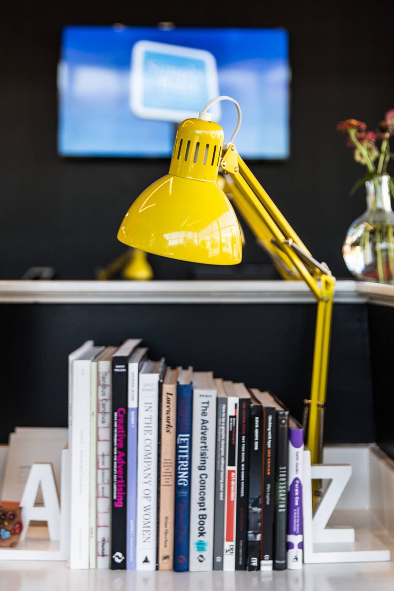 Yellow desk lamp over a row of design books between A and Z bookends