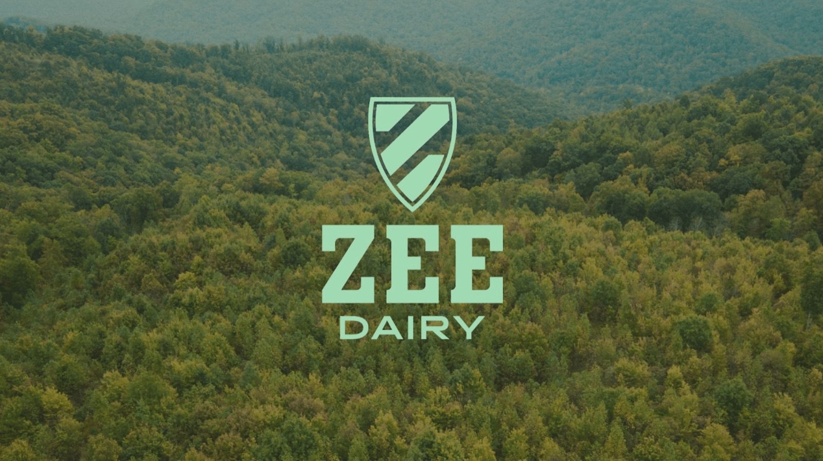 The Zee Dairy logo over an aerial photograph of forested hills