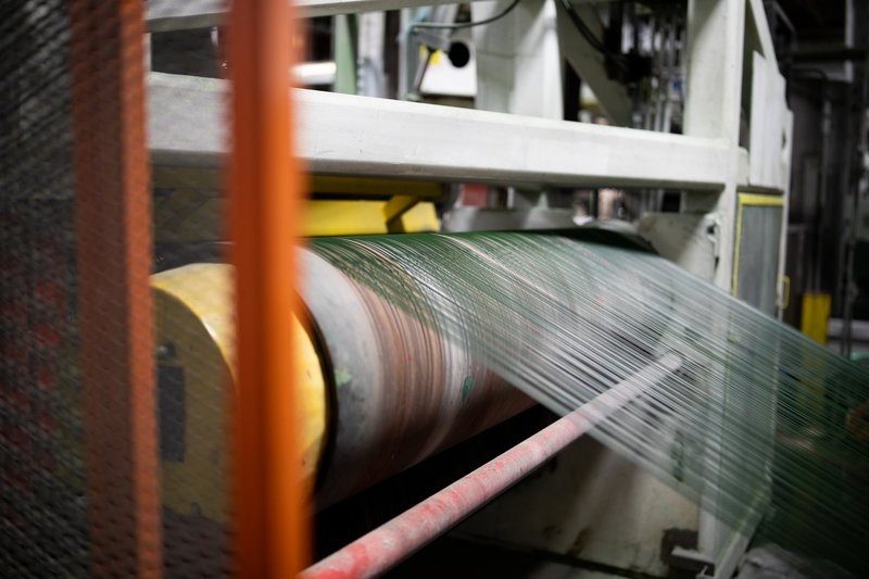 Green fiber running through a roller on a production line