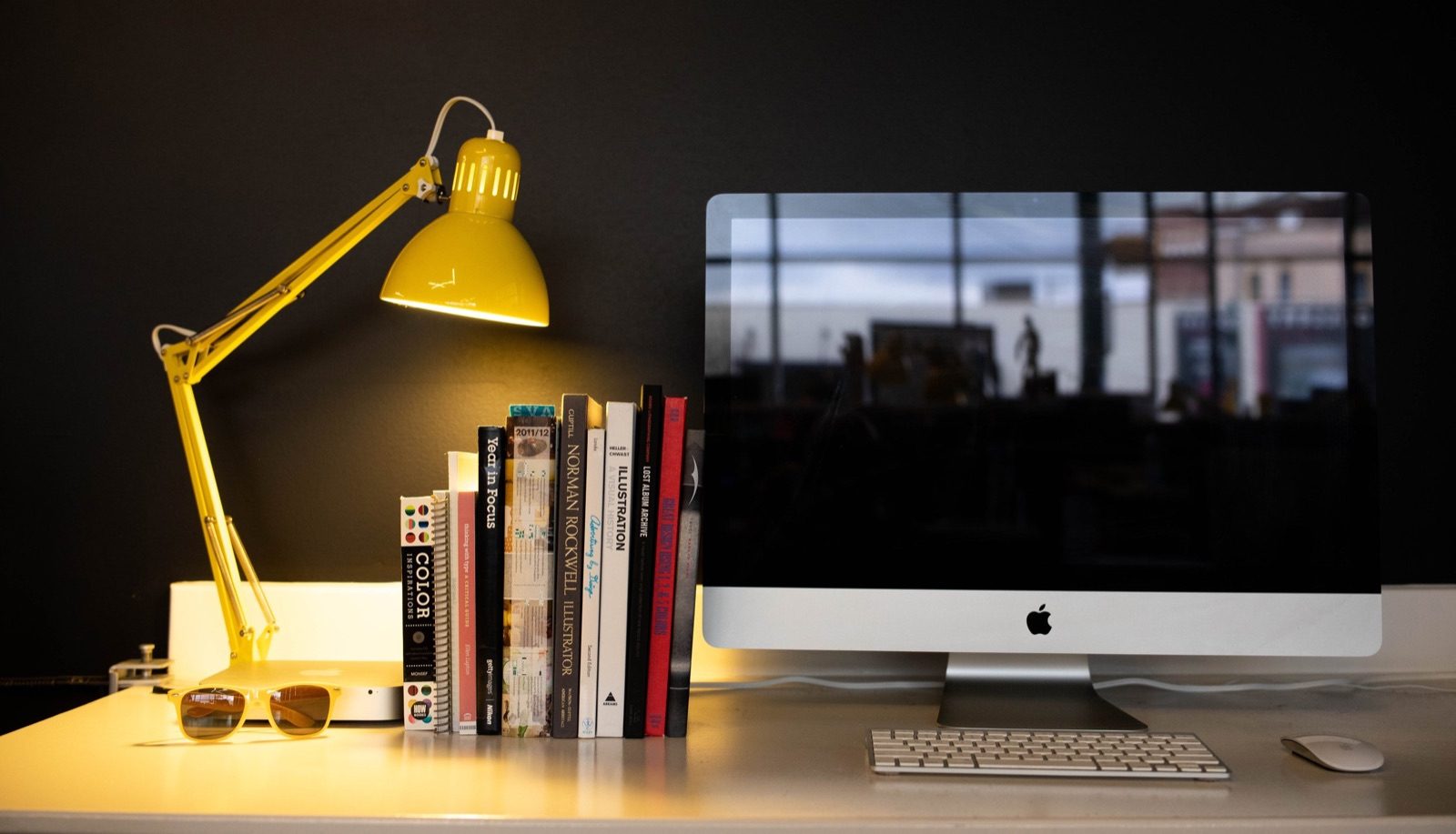 Desk with a yellow lamp, stacked books and a computer monitor