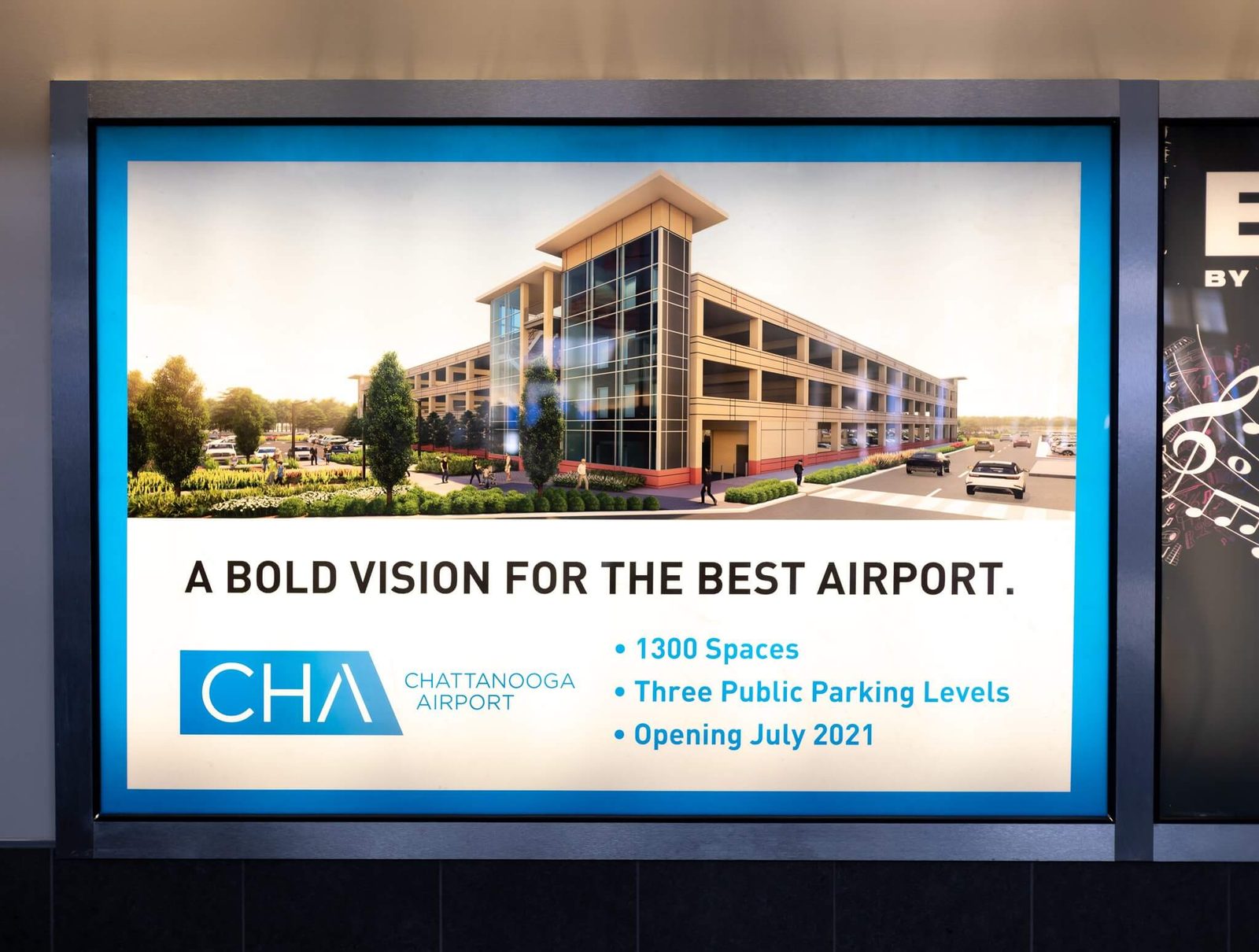A backlit terminal poster showing the new parking structure, headlined 'A bold vision for the best airport'