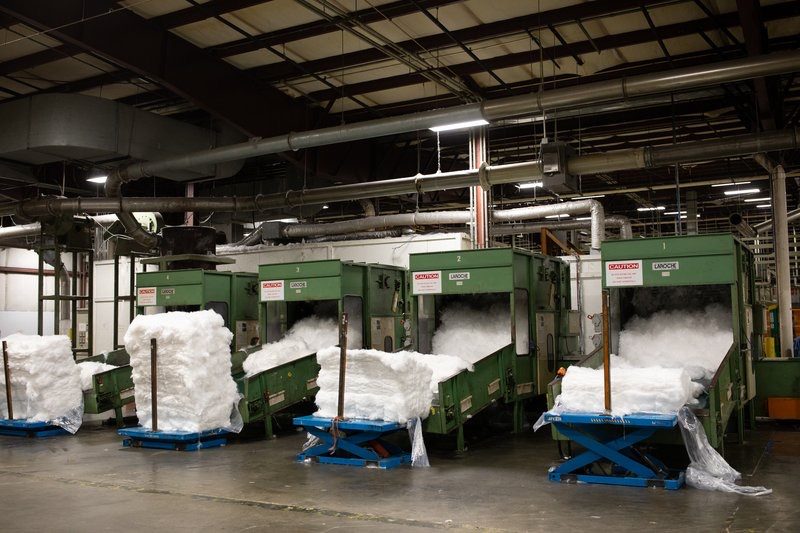 Pallets of white bales lined up beside green machines in a warehouse