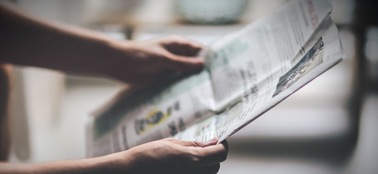 Hands holding an open newspaper
