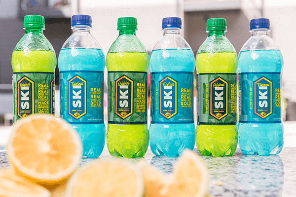 Row of SKI soda bottles in the new packaging beside sliced citrus