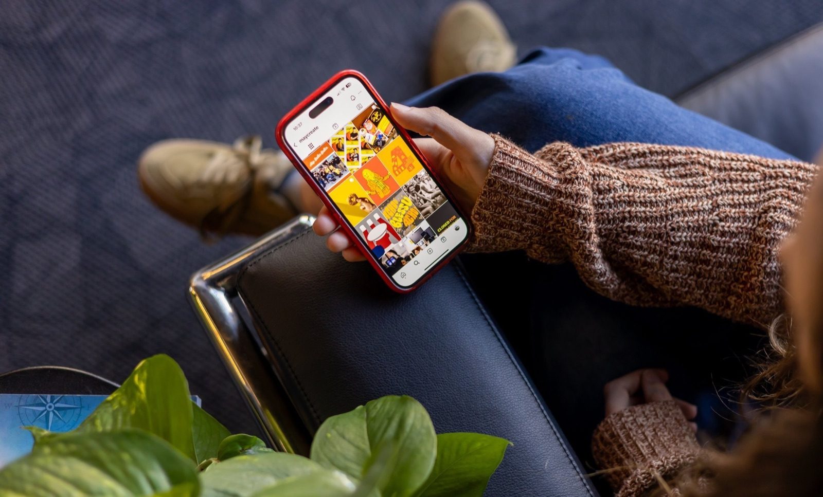 Someone scrolling a social media feed on a phone while sitting in an armchair