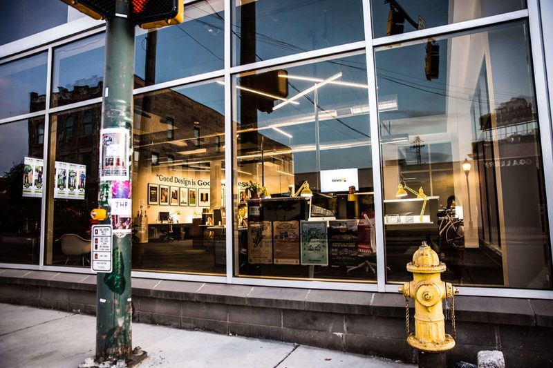 Street corner with a yellow fire hydrant outside Maycreate's glass storefront