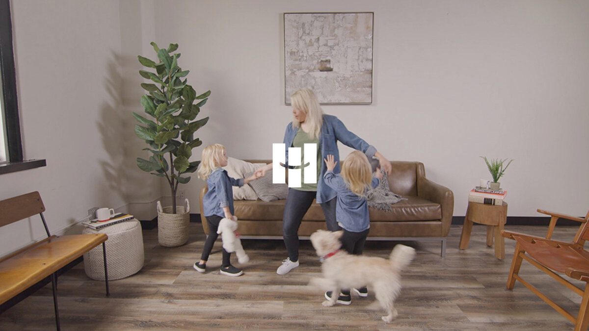 Video still of a living room with a woman, a child and a fluffy dog on new vinyl plank flooring
