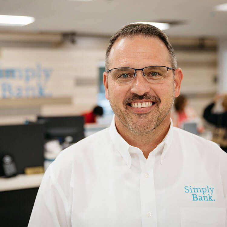 Smiling man in a white Simply Bank shirt inside the branch