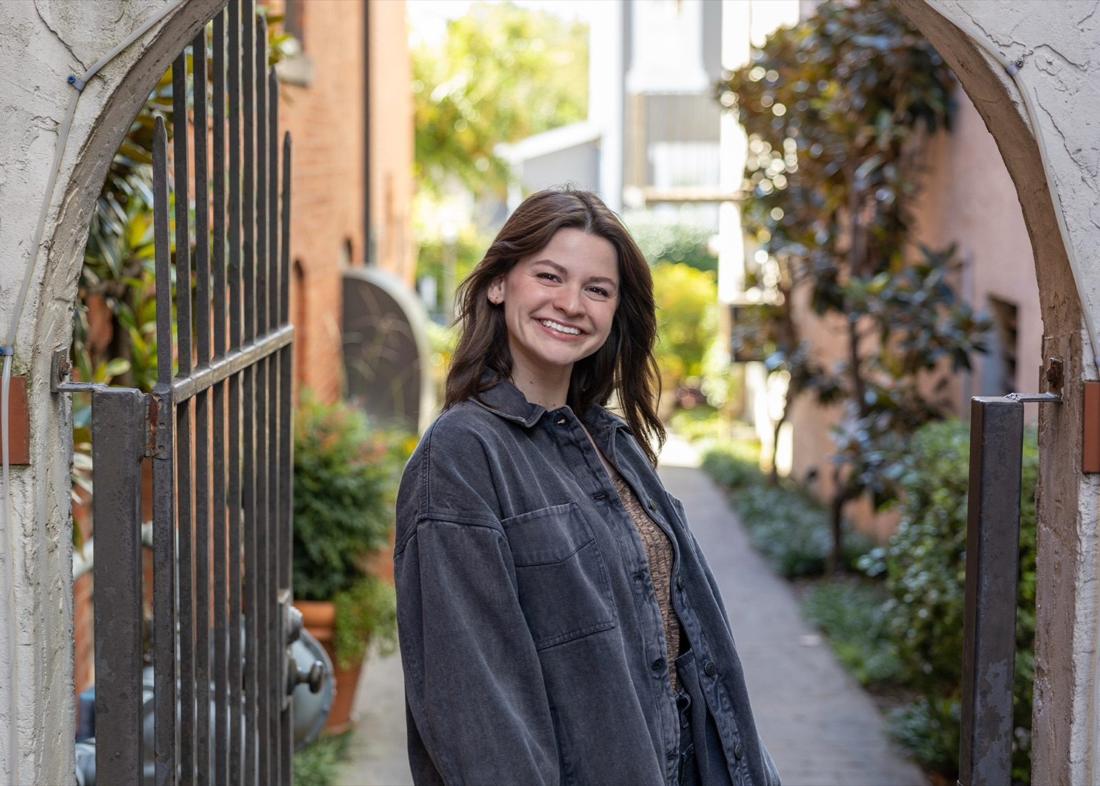 Abigail Bowman smiling in a brick archway that opens onto a garden path