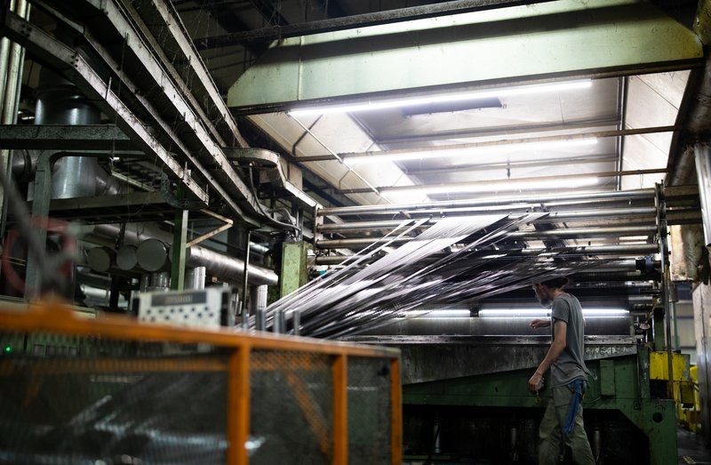 Long view down a factory aisle of extrusion lines under yellow rails