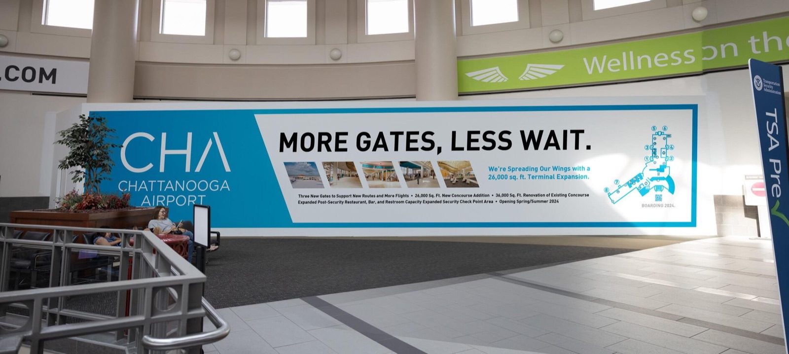 A long wall graphic in the airport terminal reading 'More gates, less wait'