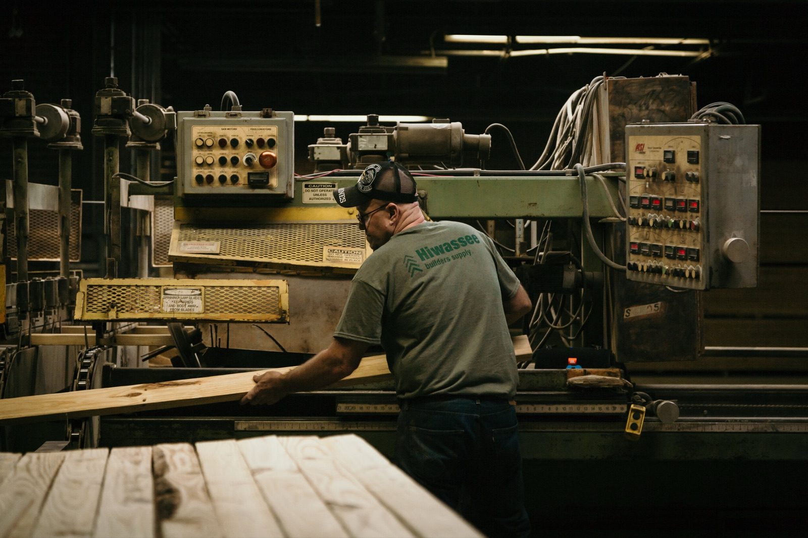 A worker feeding timber through a saw on the mill floor