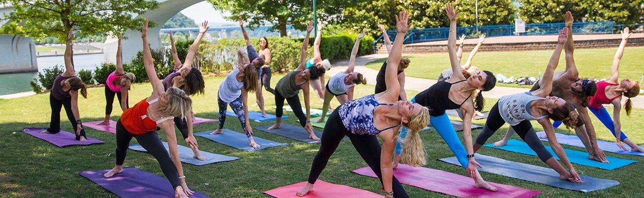 Rows of people doing yoga on mats in a park