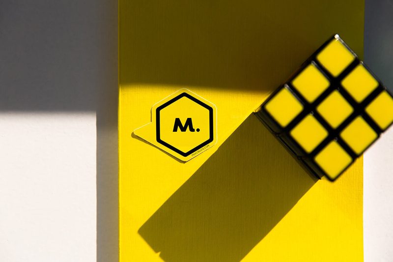 Yellow Maycreate notebook and a Rubik's cube on a yellow surface