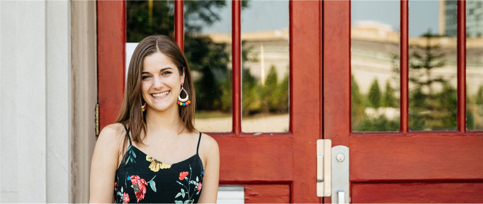 Sophia Wegman in a floral dress in front of red doors