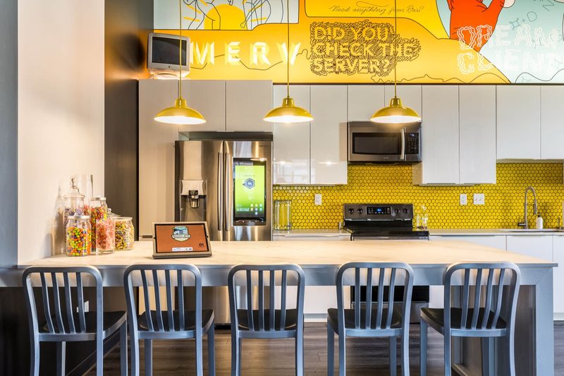 Office kitchen with a yellow tile backsplash and a mural reading Did You Check the Server