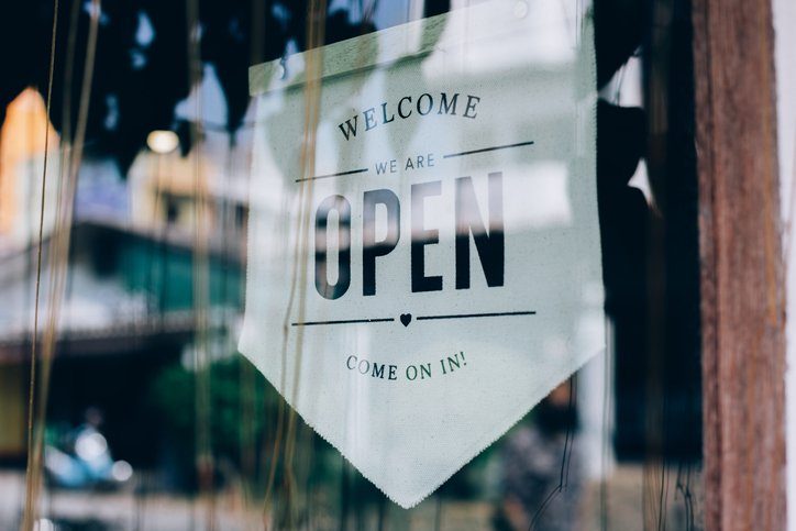 Welcome, We Are Open sign hanging in a shop window