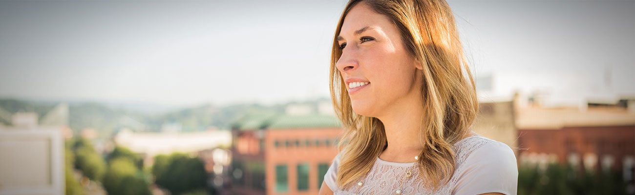Jen smiling in profile against a blurred rooftop skyline