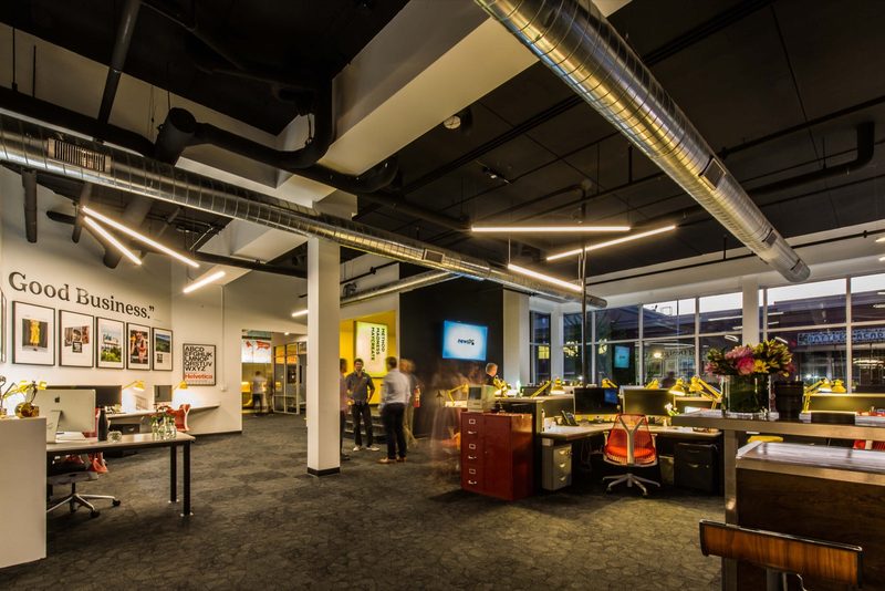 Open office with exposed ductwork, desks and the framed work wall