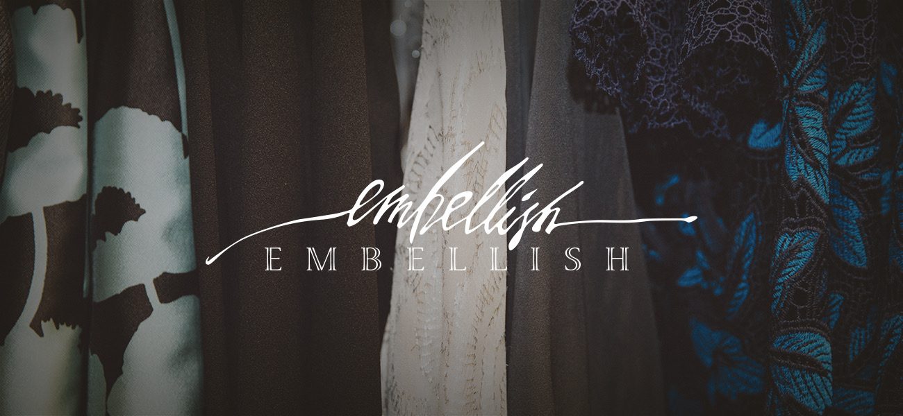 Embellish boutique logo over a display of clothing