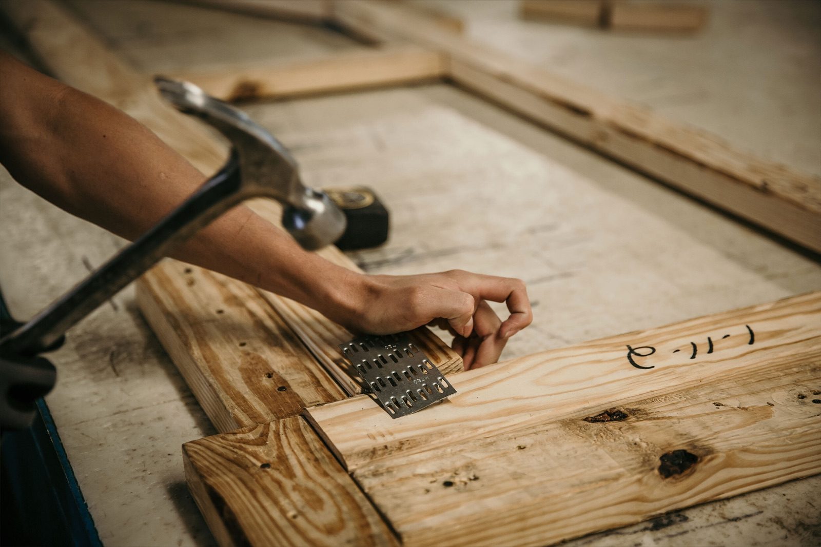 A worker hammering a metal plate into a timber joint