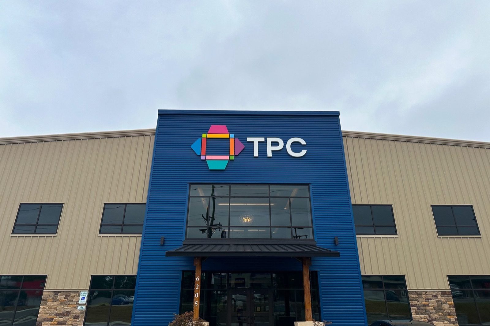 The TPC building exterior, a blue and tan warehouse front with the TPC logo above the entrance
