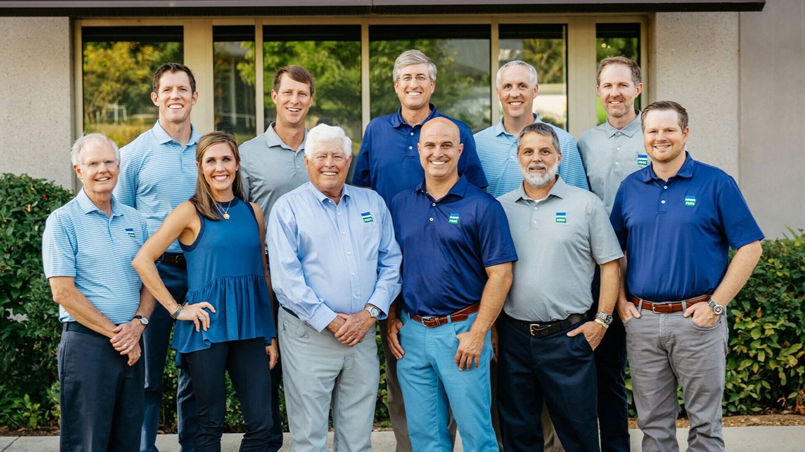 Orthodontics team in blue shirts posing outside a brick building