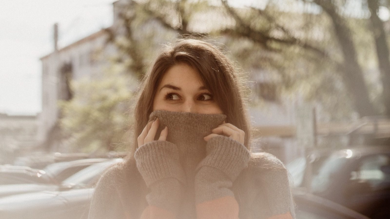 Woman in a gray sweater pulled up over her nose, smiling with her eyes