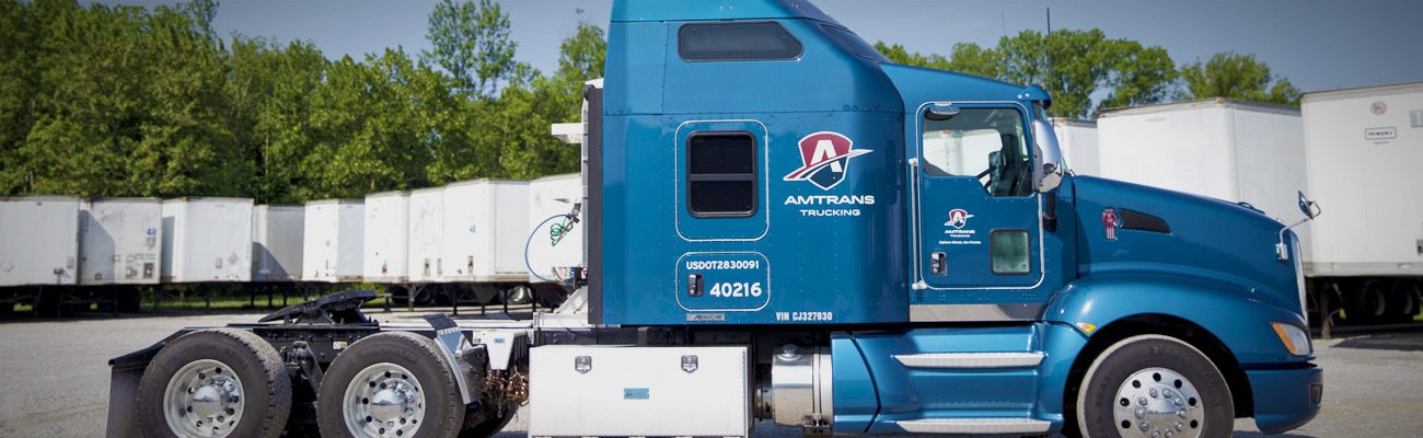 Blue semi truck cab in front of a row of white trailers