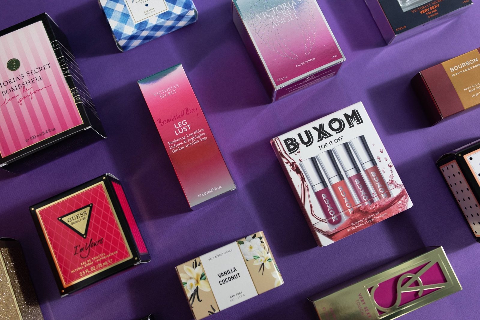 Cosmetics and fragrance packaging arranged on a purple background