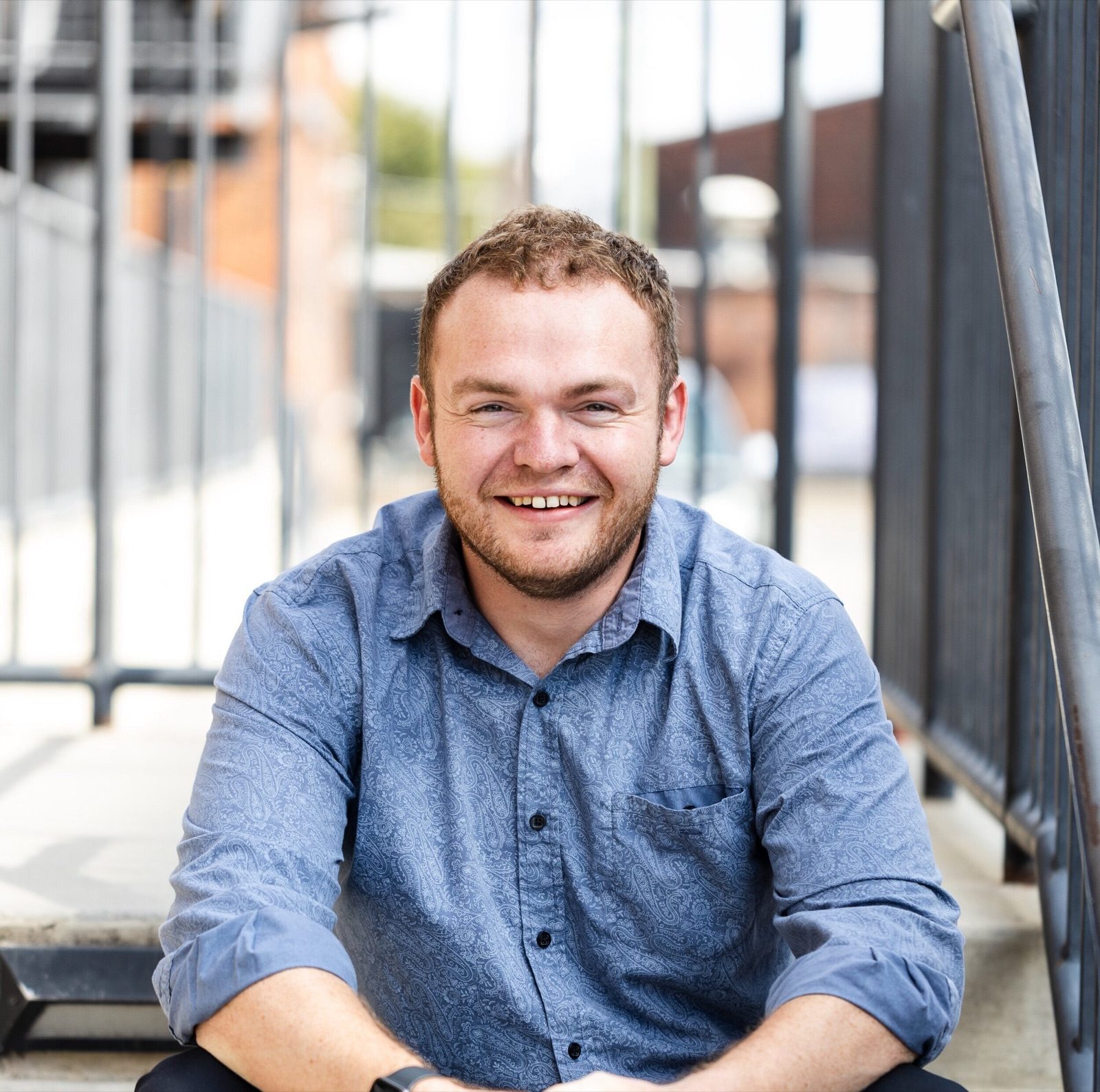 Mark Domeracki in a blue shirt smiling on a rooftop patio