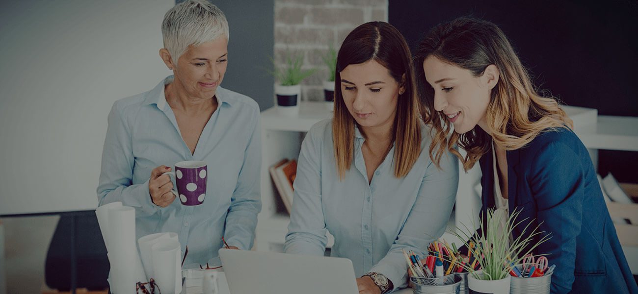 Three women looking at a laptop together in an office