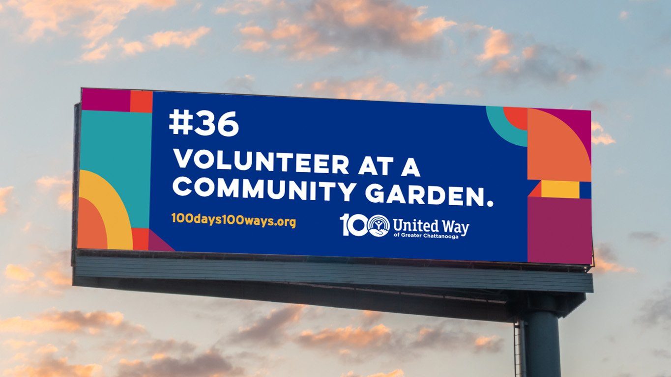 A United Way billboard at dusk reading 'Volunteer at a community garden'