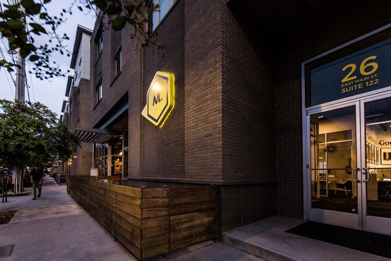 Maycreate's yellow M sign above the entrance at 26 East Main Street