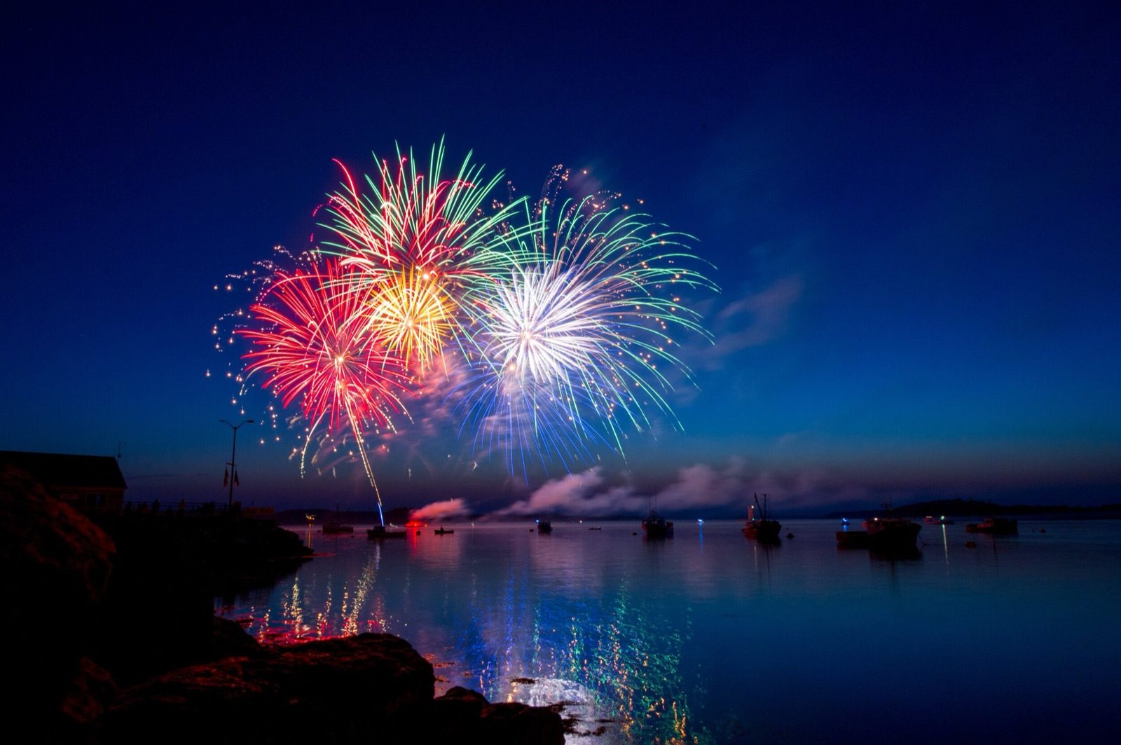 Fireworks bursting over a harbor at dusk