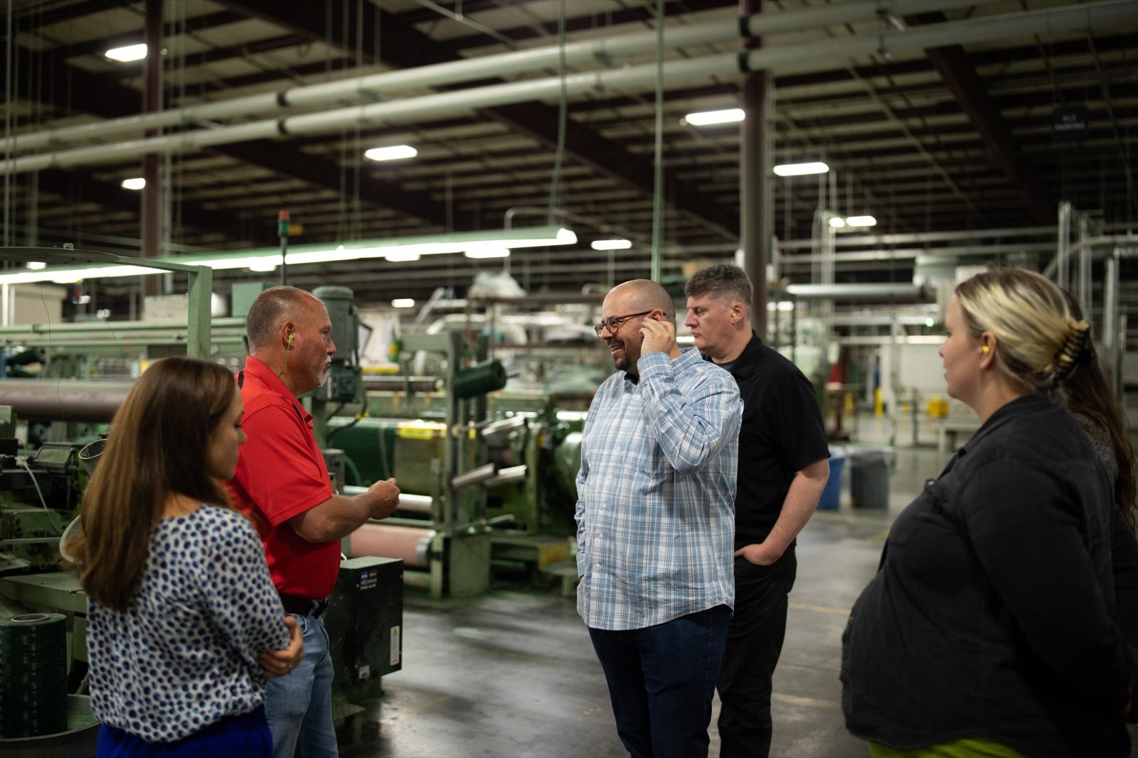 Maycreate team touring a manufacturing floor with a client in a red shirt