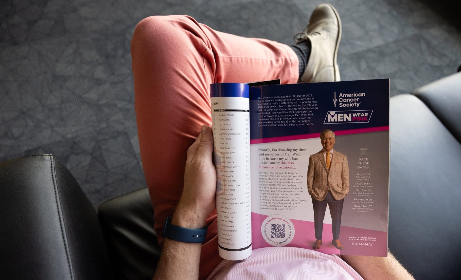 Person in pink pants reading a magazine open to an American Cancer Society Real Men Wear Pink page