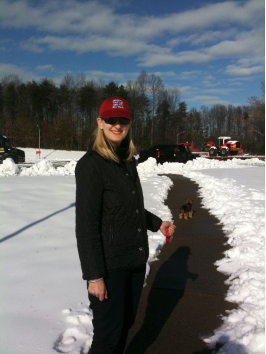 A woman in a red cap standing beside a shovelled path cut through deep snow