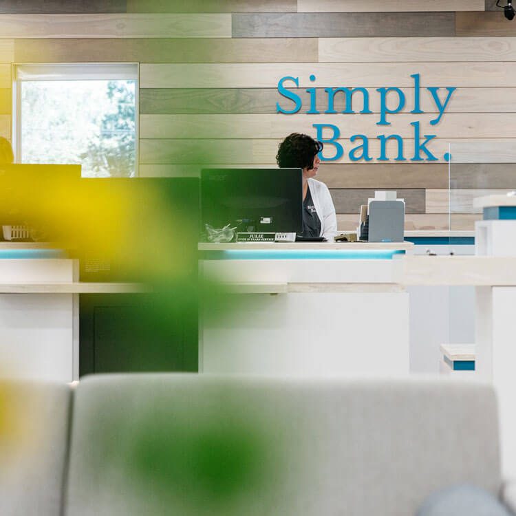 Simply Bank teller counter with the logo on a wood-slat wall