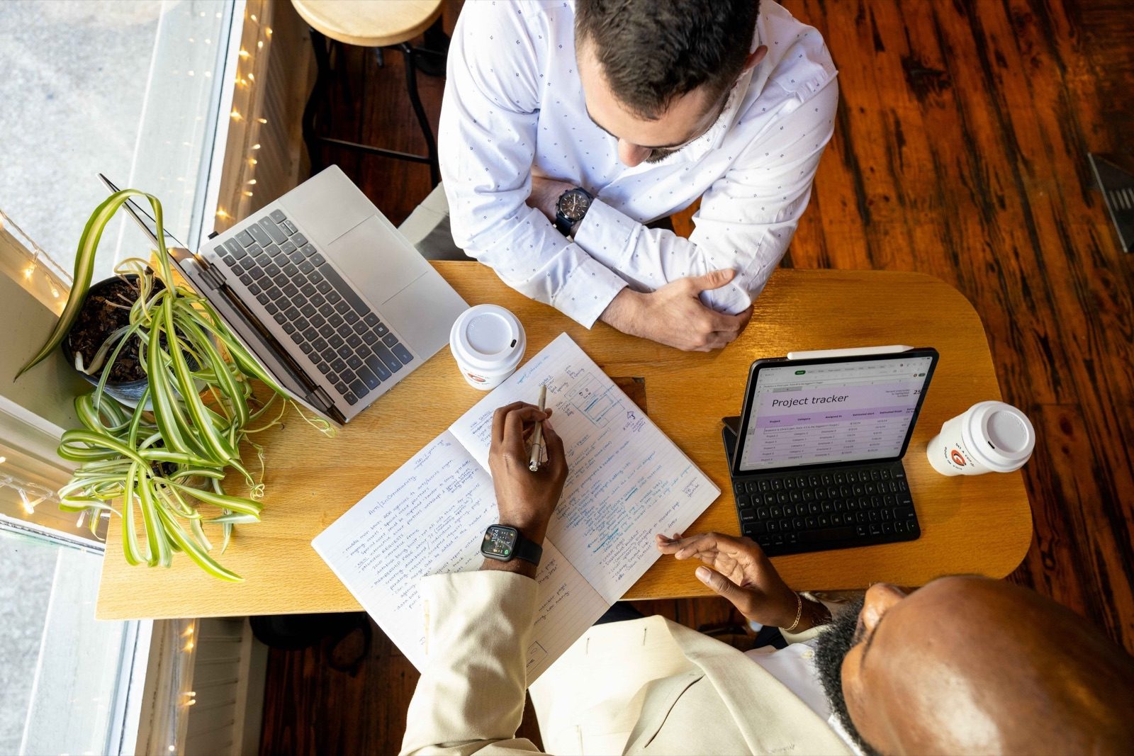 Two people reviewing printed reports and a tablet across a table, seen from above
