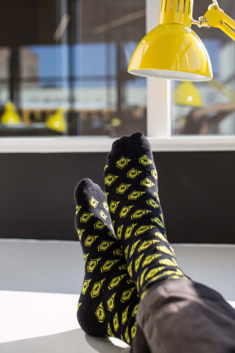 Feet in yellow patterned socks propped on a desk under a yellow lamp