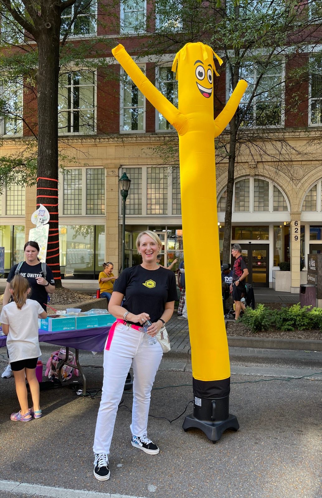 A volunteer standing beside an inflatable tube figure at a street event