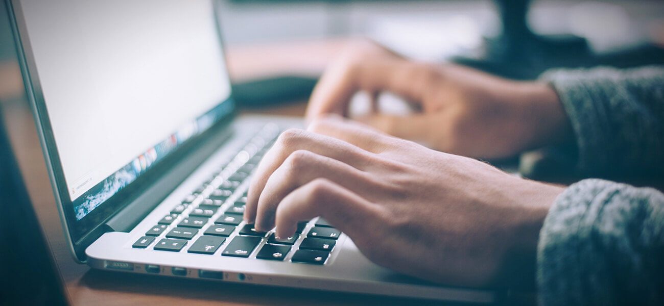 Hands typing on a laptop keyboard