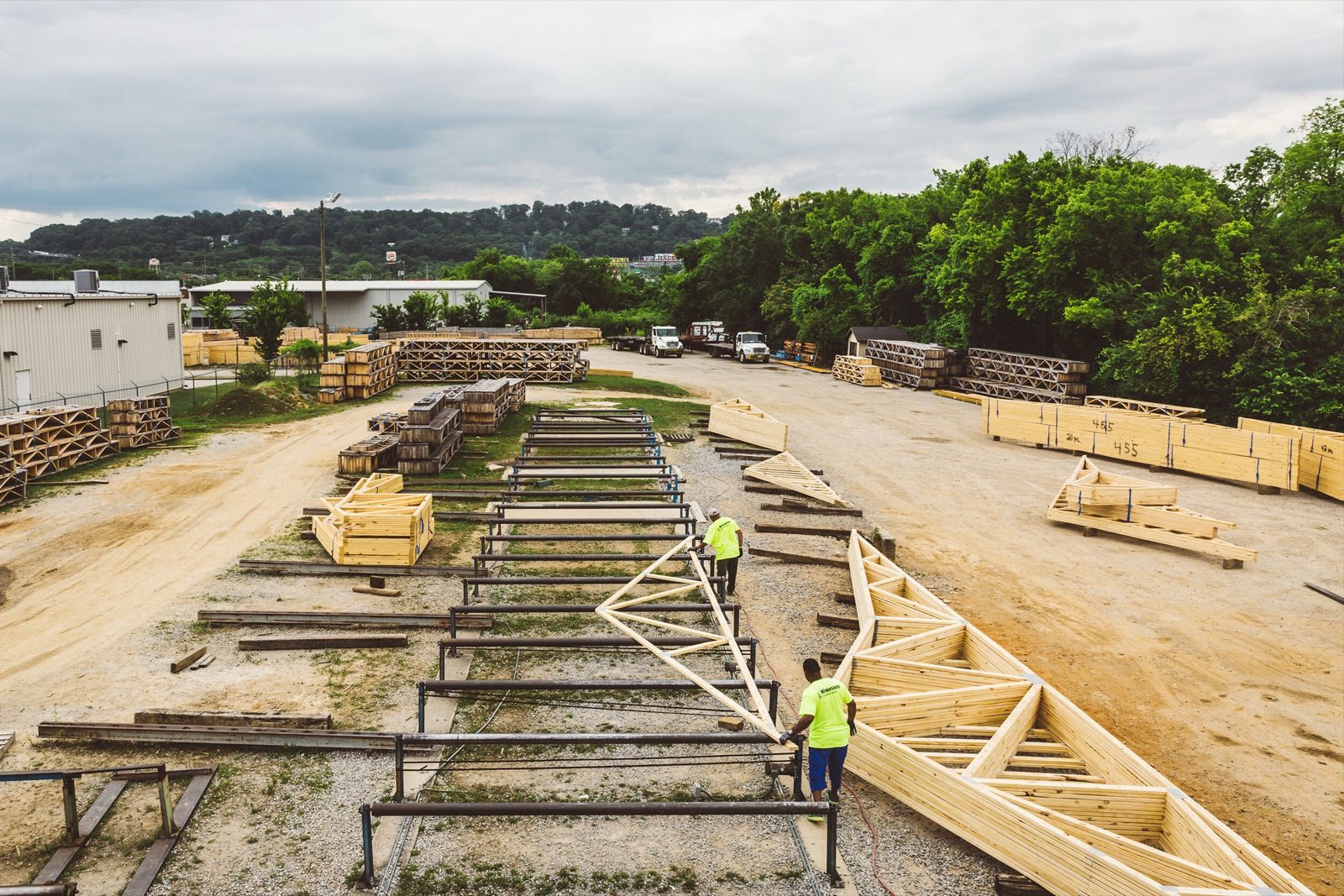 Timber trusses laid out in the yard with two workers walking between them