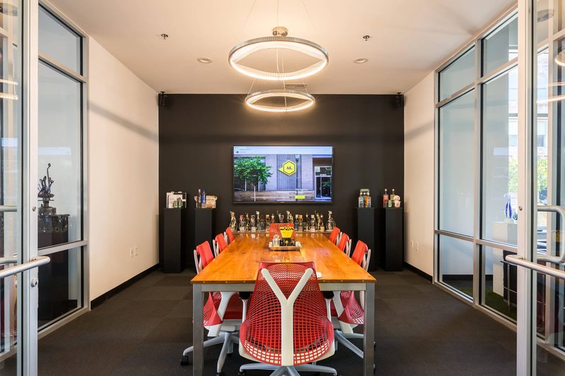 Glass-walled conference room with an orange table and red chairs