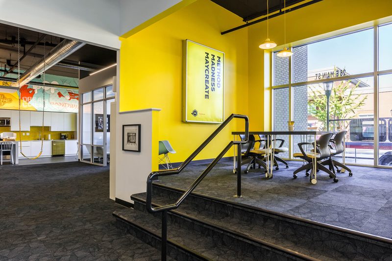 Yellow entrance stair with a Maycreate wall sign and a conference table beyond