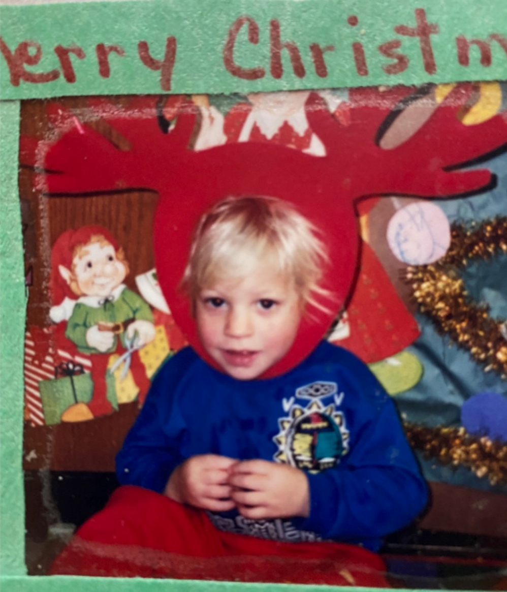 A toddler in red felt reindeer antlers, framed in a handmade Merry Christmas card