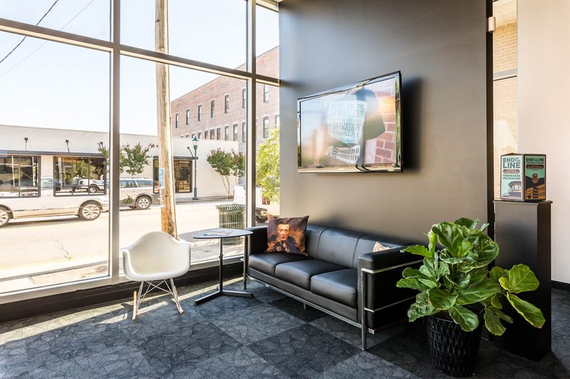 Corner lounge with a black leather sofa and windows onto the street